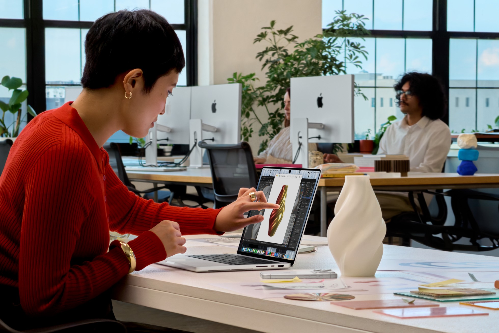 Una persona sentada en una oficina toca la pantalla de su MacBook Pro con PROLED XDR