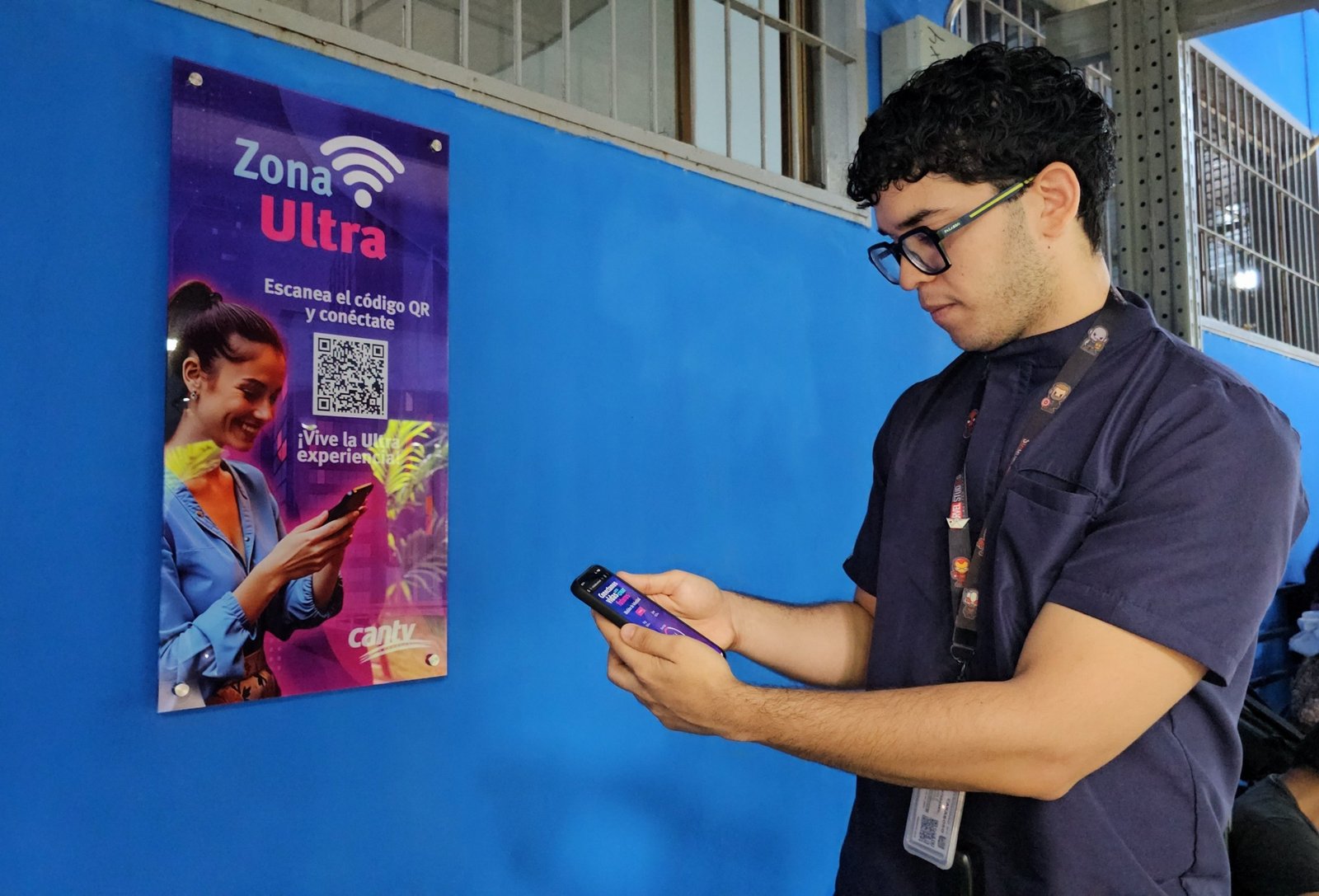 Trabajador de Cantv escanea con su teléfono el código QR de un cartel de Zona Ultra en una pared azul