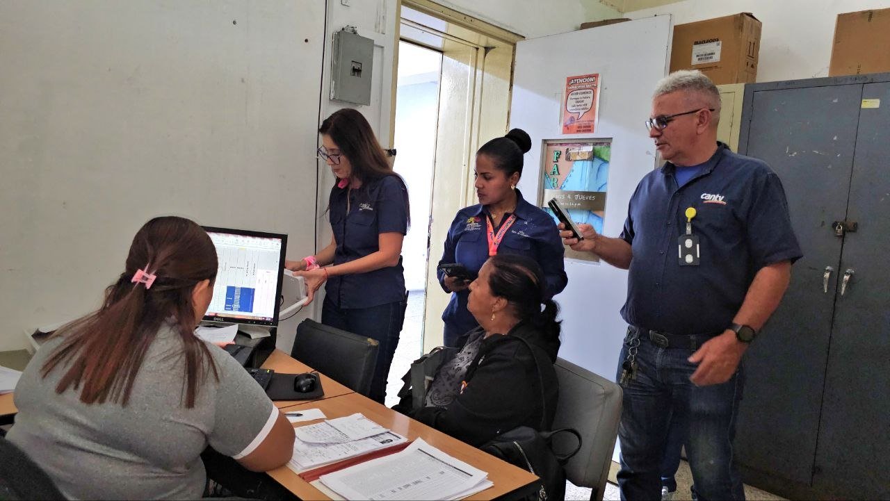 Personal de un centro de salud trabaja en una computadora mientras trabajadores de Cantv revisan la conexión