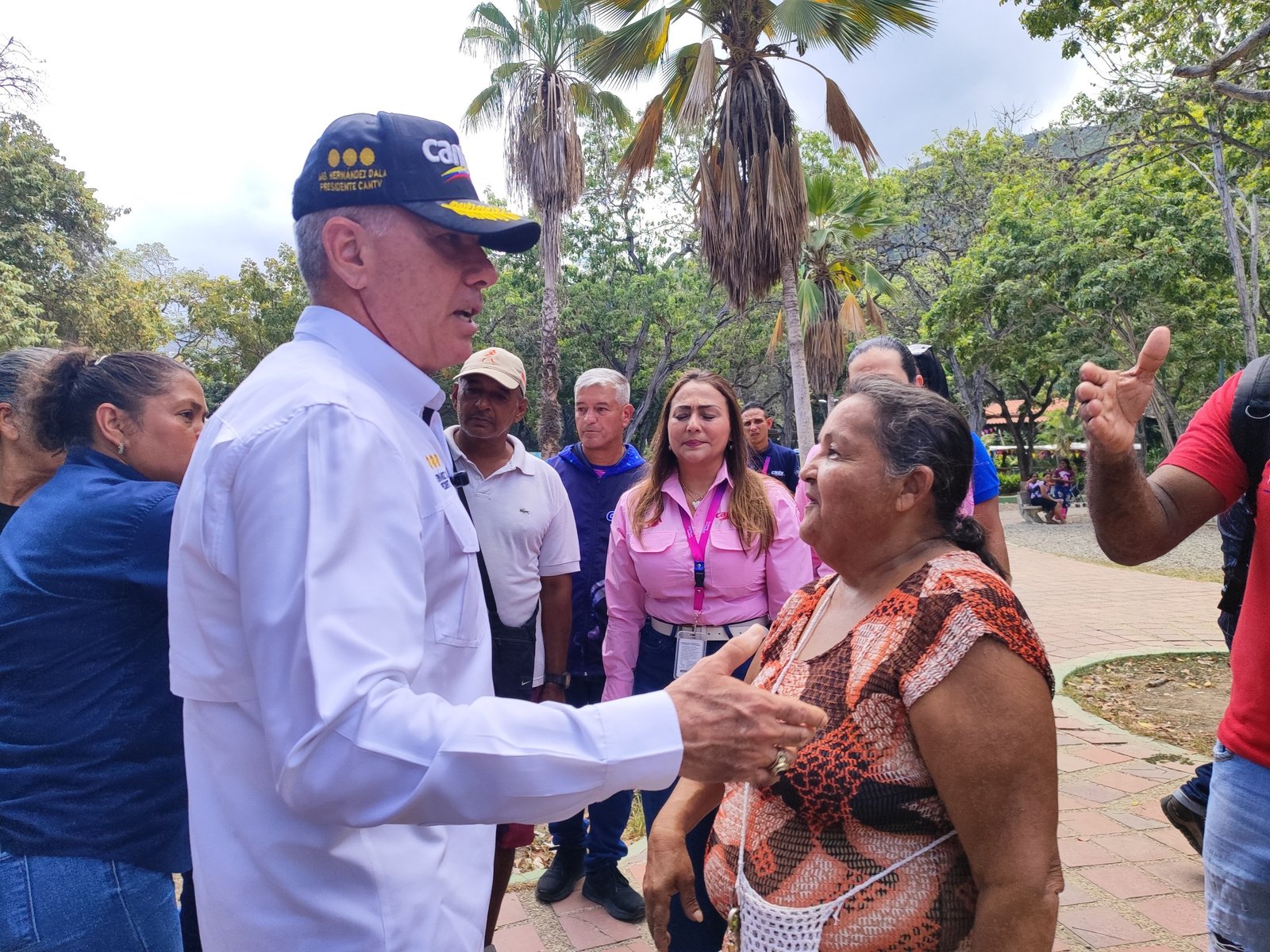 Hombre con gorra y camisa blanca conversa con una vecina durante un recorrido de Cantv