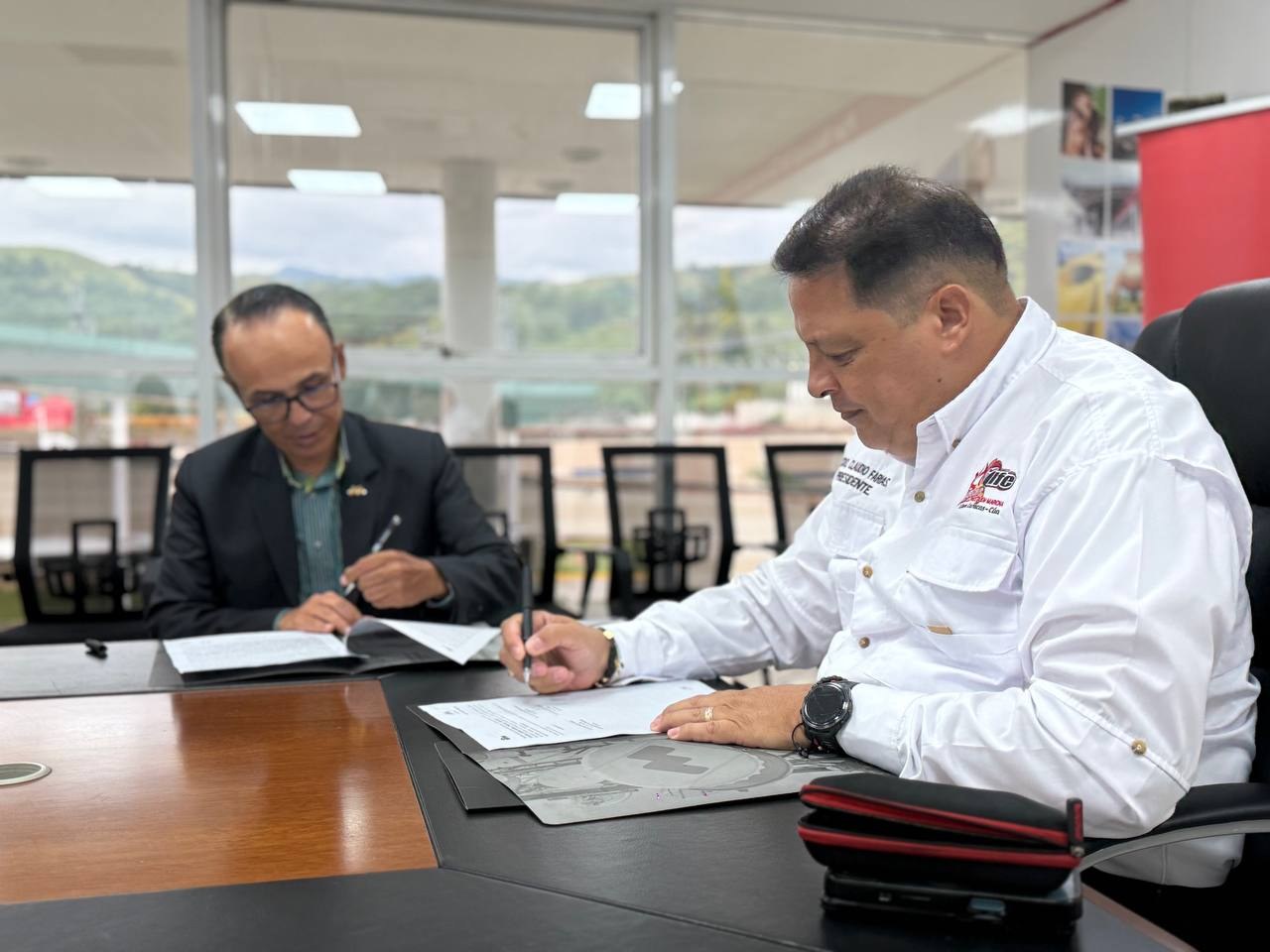Representantes de Movilnet y del IFE firman el convenio en una mesa de reuniones
