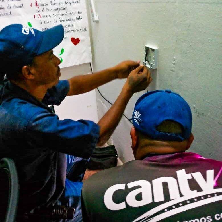 Técnico de Cantv instala una caja de conexión de fibra óptica en una pared